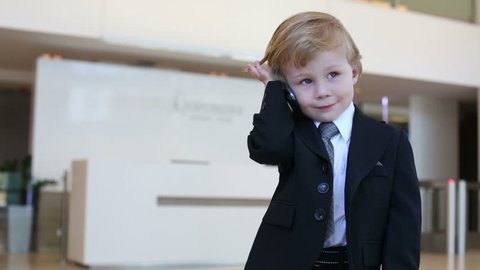 Little cute boy in business suit and tie talks on phone