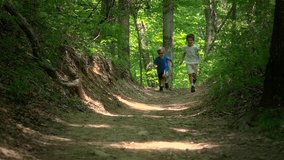 Two boys running in the forest together laughing and playing and jumping in slow motion.
full hd video clip