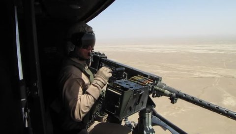 Afghanistan, Circa 2010: Door gunner of helicopter fires machine gun at enemy target in desert of Afghanistan, Circa 2010
