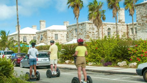 BERMUDA - OCTOBER 2013: Cruise Ship Passenger Tourists Enjoying a Segway Excursion in the Tropical Bermudan Islands on a Sunny Day with Green Palm Trees, Historic Architecture and a Blue Sky.