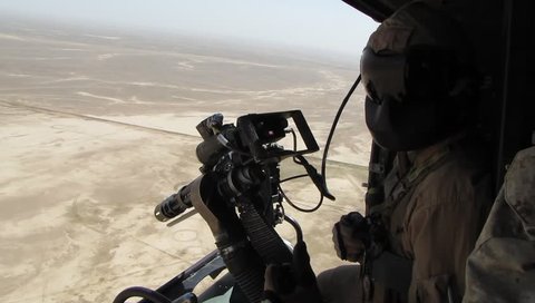 Anti-Missile Flares shot from helicopter as door gunner looks over desert for enemy targets