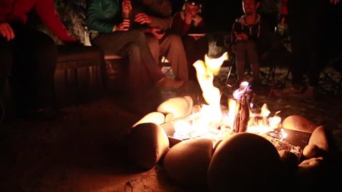 Family sitting around campfire while camping