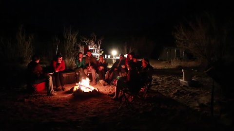 Family sitting around campfire while camping