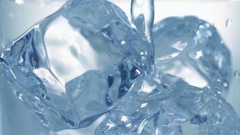 Clear cold water is pouring into a glass with ice cubes. Slow motion filmed at 250 fps. 