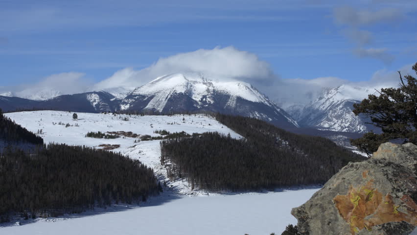 Time lapse of clouds churning above snow-capped peaks in the Rocky Mountains of