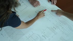 Team of architects working together, examining blueprints, choosing, talking, correcting.