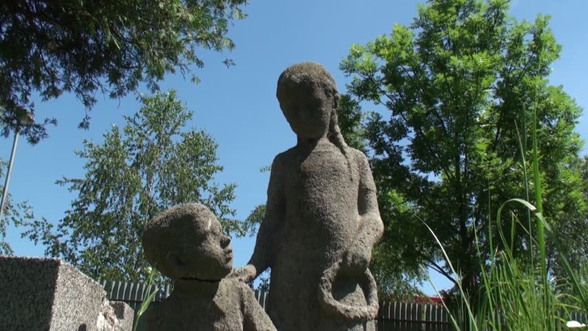 Camera pass over statue of two children on the cemetery. 