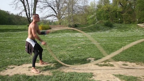 Sports man is training with undulating ropes