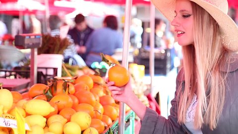 Blonde girl at the market picking fruit స్టాక్ వీడియో