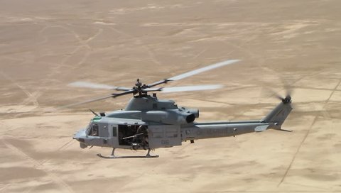 US Marine UH-1 (Huey) Helicopter Banks and Flies Away from Camera 