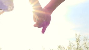 Happy couple having fun outdoors. Couple running away on the meadow. Countryside. Young Man and woman holding hands and running through a field with wild flowers. Sun flare. Slow motion video footage 