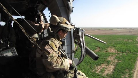 Afghanistan, Circa 2010:  air force pj with weapons rides in open doorway of helicopter in Afghanistan, Circa 2010