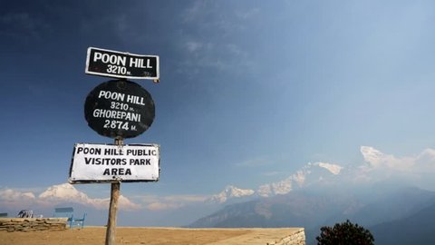Trekker reaching Poon hill altitude sign (3210 m) with beautiful view of Annapurna and Dhaulagiri range on a background, Ghorepani, Nepal. 