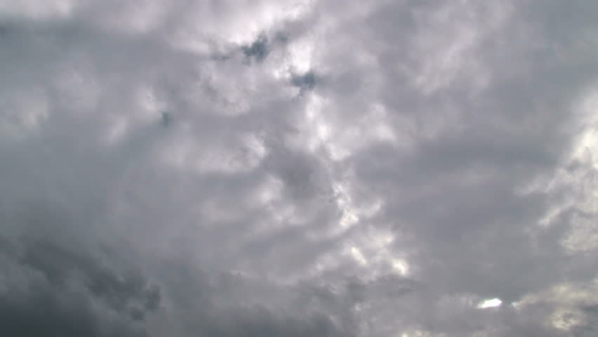 Storm clouds move fast on overcast day with sun peaking through.