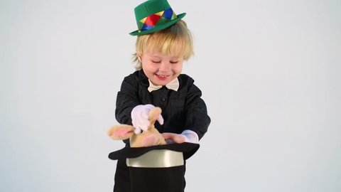 Little boy magician shows focus with rabbit in hat
