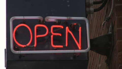 Red neon open sign with snow falling. Sound of traffic in the background.