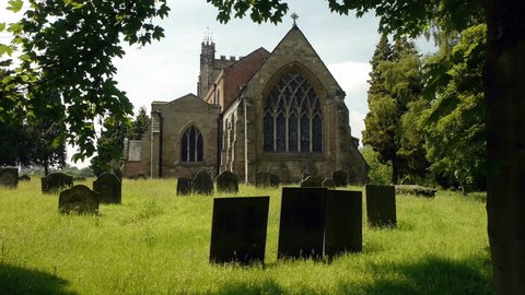 Country churchyard with gravestones.
A small church in the English Midlands with a few gravestones in a sunlit grass.