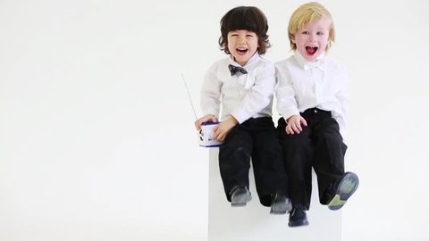 Two handsome little boys sit with wireless radio in white studio