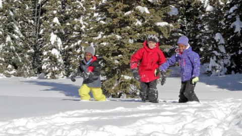 Three kids run through snow