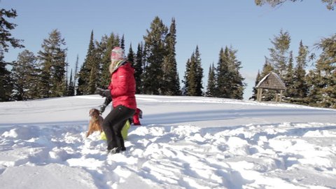 A family and dog play in the snow
