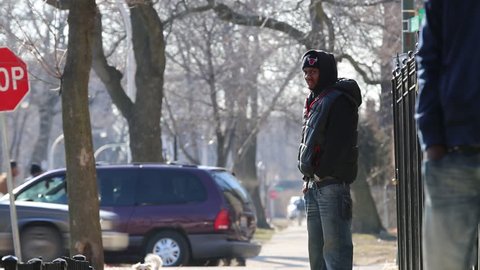 Chicago, Circa 2013: A Young African/American male wearing a hoodie sweatshirt stands on a street corner in Chicago, Circa 2013 Street corner activity in a high crime area