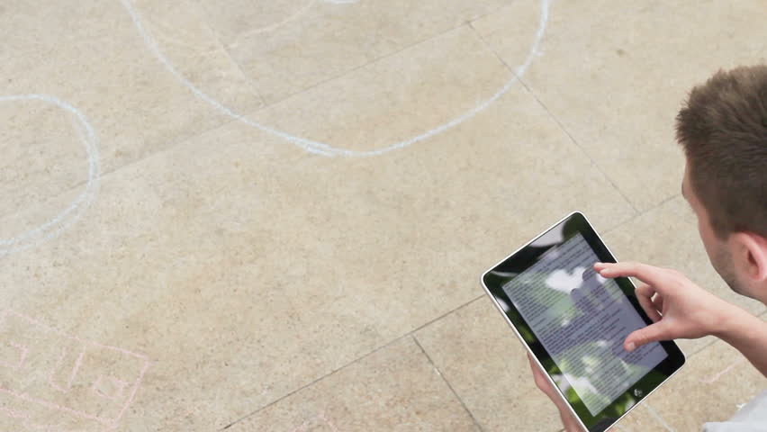Young handsome caucasian man relaxing outside, having fun with electronic device