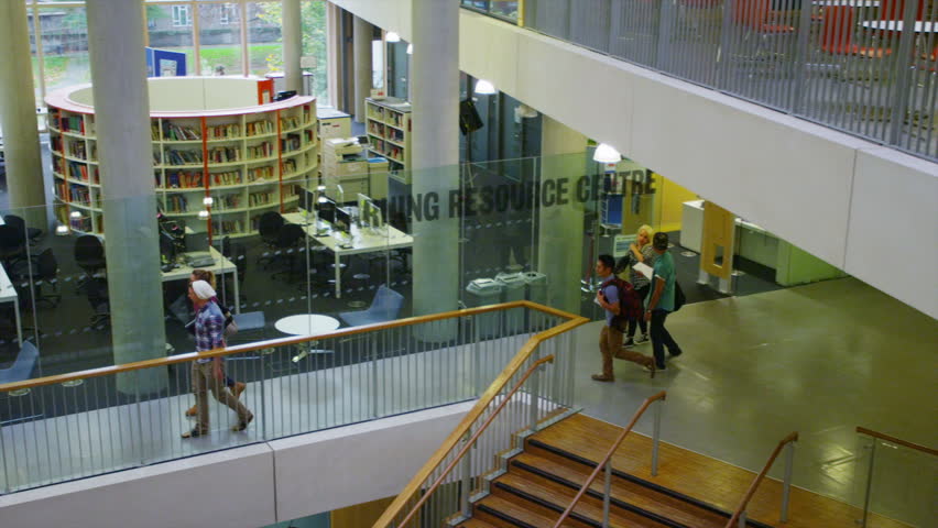 Diverse student group walking through a large modern university building.