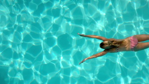 Caucasian woman swimming in the pool underwater overhead in slow motion