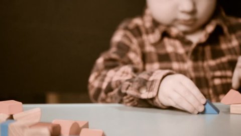 little boy making construction from wooden blocks