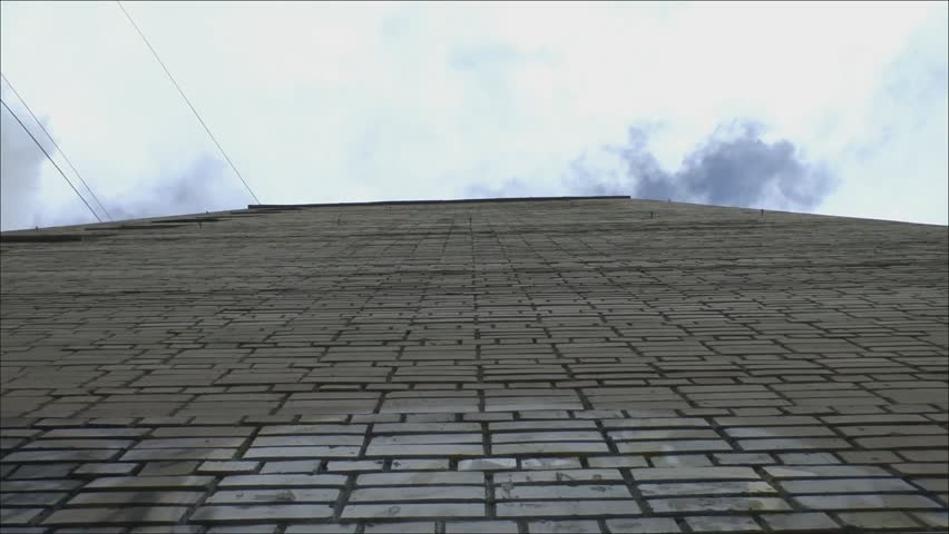 Brick wall a tall house on a background of clouds
