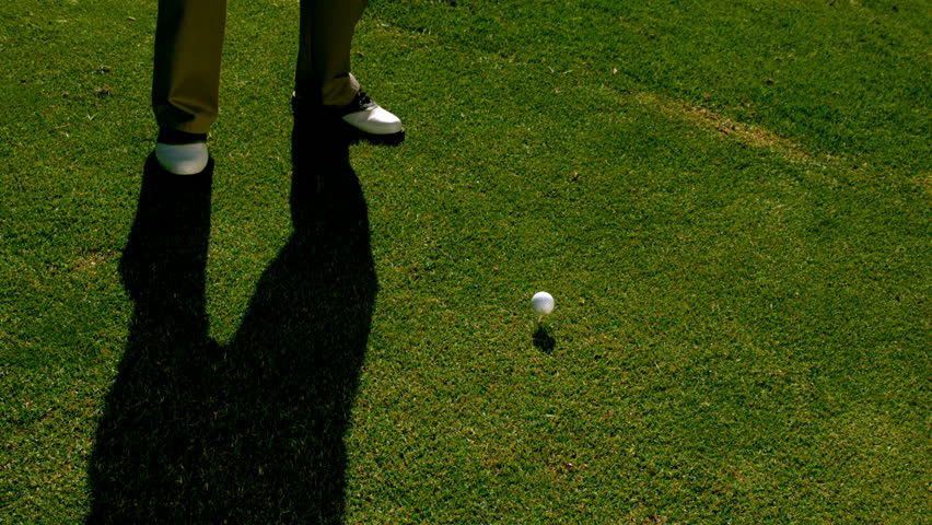 Golfer hitting the golf ball with club on the course in slow motion