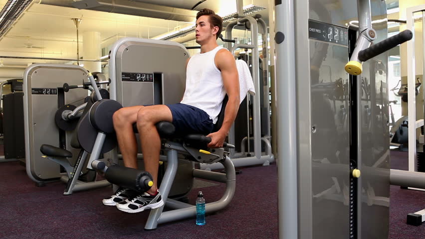 Fit man exercising his legs on weight machine at the gym