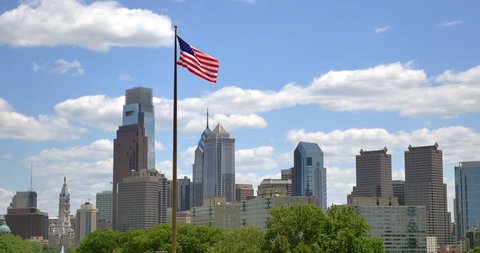 4K American flag stars and stripes  floating in front of the  - Philadelphia skyline - Pennsylvania - USA स्टॉक वीडियो