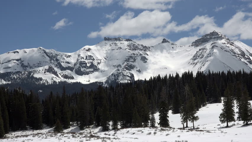 Rocky Mountains snow peaks clouds fast time lapse. Beautiful mountains near Telluride, Colorado. Spring time with snow and forest in nature. Clouds drifting along top of Rocky Mountain peaks. Royalty-Free Stock Footage #6569996