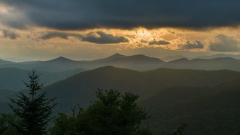 Moody Scene at Dusk Over the Dark Layers of the Appalachian Mountains near Asheville in Western North Carolina Featuring Golden Sun Rays Illuminating the Clouds over the Forest.