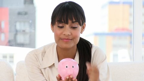 Ethnic businesswoman holding a piggy-bank at work