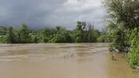 Beautiful landscape of flood river,sunny day,dark clouds,forest coast in the background,wide angle.Panoramic view of river flow.Muddy river rushes.Raging river.Abstract natural disasters,wilderness.