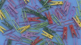 Assorted coloured  paper clips rotating on a blue background.  