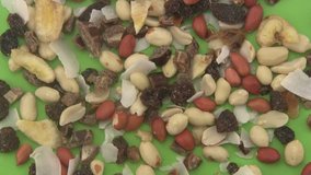 Close up of tropical dried mixed fruit rotating on green background.
