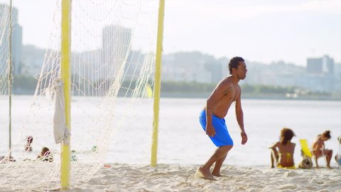 Young man attempts to block a soccer goal at the beach
