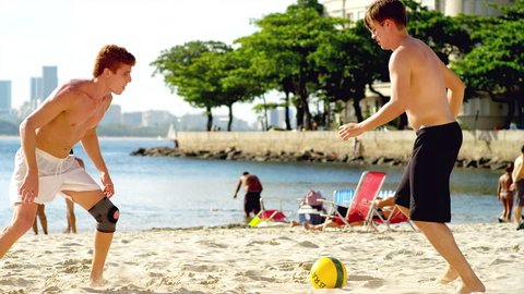 Friends play soccer on the beach