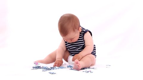 Baby playing with puzzle against white background