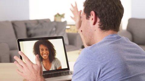 Caucasian man talking to African female on laptop computer. Couple having video chat to stay connected while at home