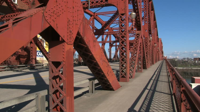 Person rides bicycle over Portland, Oregon bridge on sunny day.