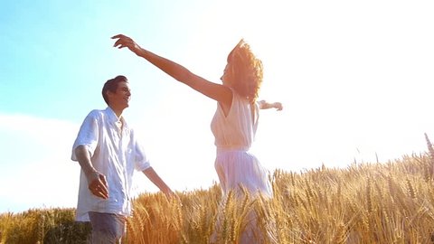 Young ,happy woman run into the arms of her boyfriend, love in the wheat field at sunset.Flare light, slow motion, high speed camera, flare light