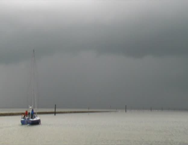 Sailing boat leaving a save harbor during thunder storm