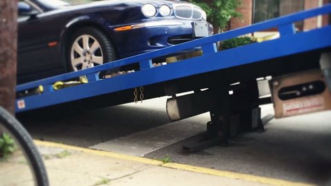 A car gets loaded onto the bed of a towing truck.