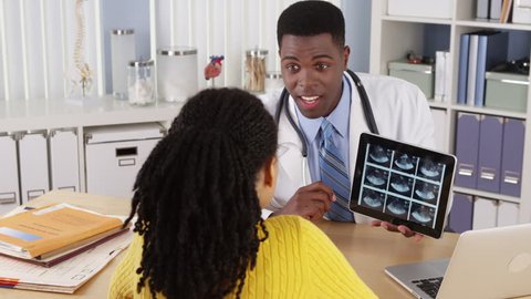 African American OBGYN using tablet to show ultrasound to patient at desk