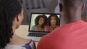 Young black couple having internet video chat with two friends on laptop