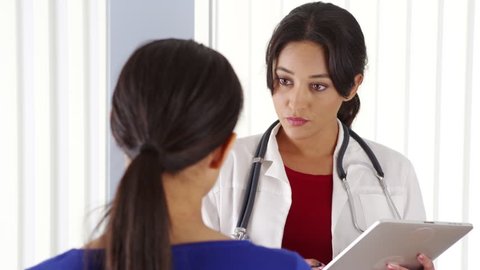 African American patient talking to hispanic doctor using tablet pc